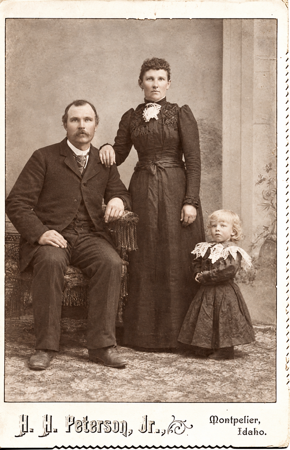 Historical photograph of a seated man, a standing woman, and a young child